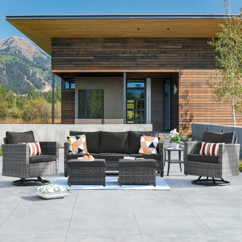 ovios dark gray wicker outdoor conversation set with sofa chairs and ottomans arranged on a patio