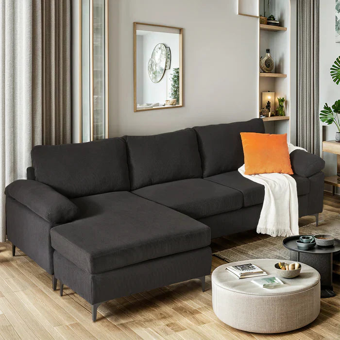 Relax on this Ovios Corduroy sectional sofa, featuring dark upholstery, slim legs, an orange cushion, and white throw