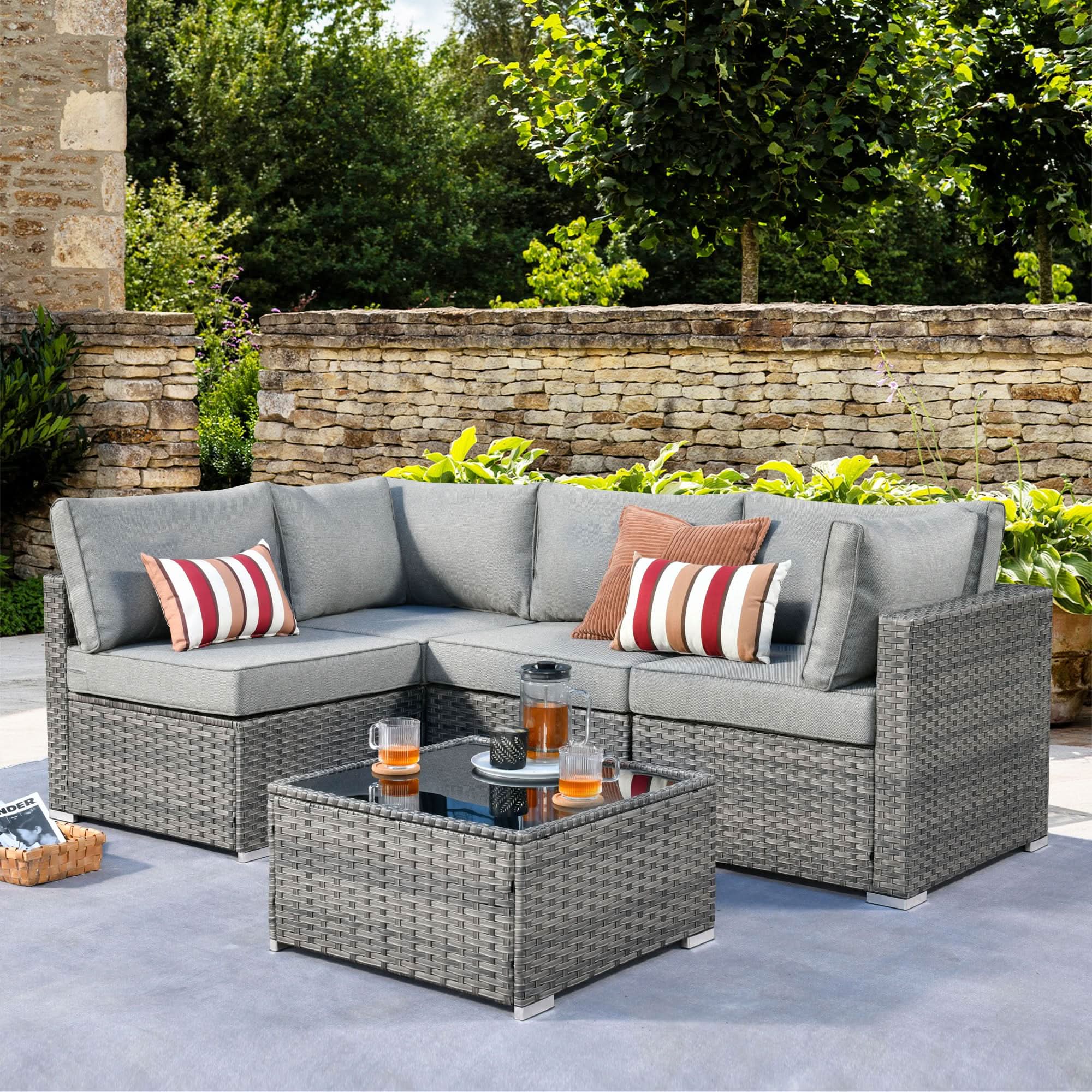 OVIOS grey wicker outdoor sectional set with coffee table, grey cushions, and striped accent pillows.Dark Grey