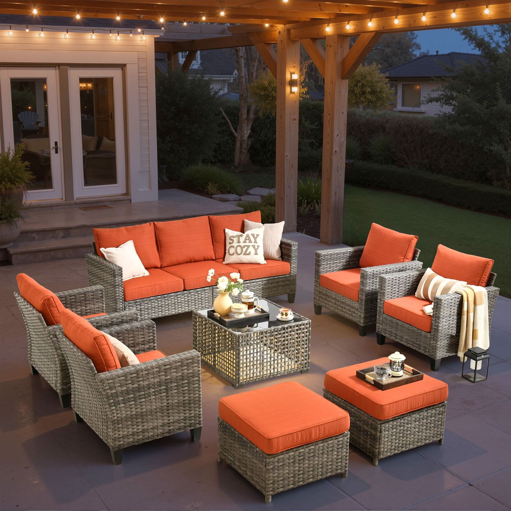 OVIOS grey wicker 8-piece patio conversation set with orange cushions and solar table.